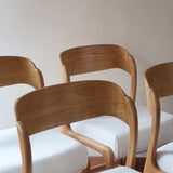 Lot de 4 chaises Baumann modèle Bémol en bois clair finition mate avec assises épaisses retapissées en bouclette écru.