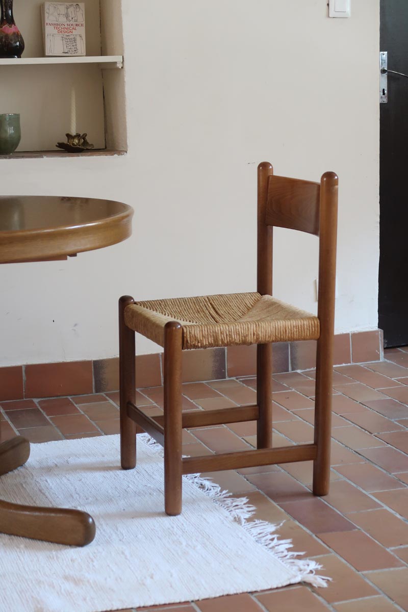 Lot de quatre chaises vintage des années 60 en chêne massif avec assise en paille tressée, style Charlotte Perriand, posées sur un sol en carrelage rouge.