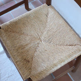 Lot de quatre chaises vintage des années 60 en chêne massif avec assise en paille tressée, style Charlotte Perriand, posées sur un sol en carrelage rouge.