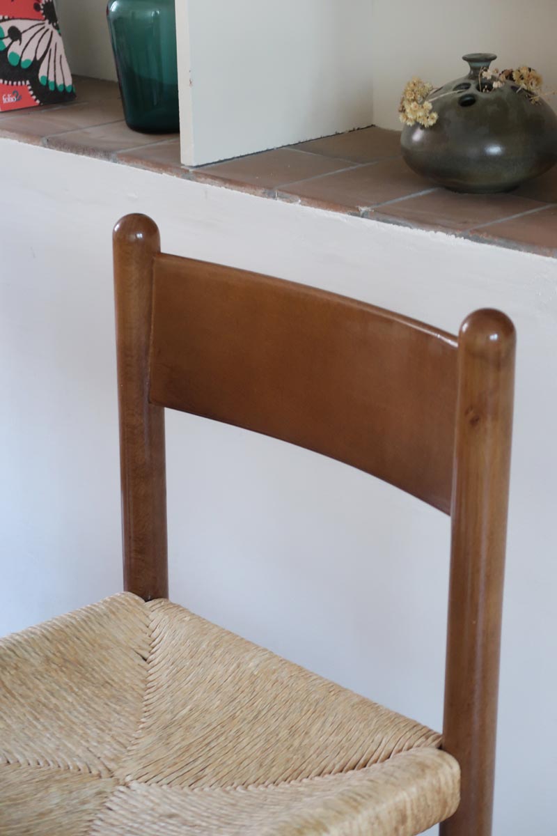 Lot de quatre chaises vintage des années 60 en chêne massif avec assise en paille tressée, style Charlotte Perriand, posées sur un sol en carrelage rouge.