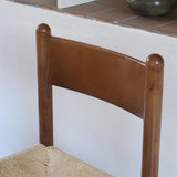 Lot de quatre chaises vintage des années 60 en chêne massif avec assise en paille tressée, style Charlotte Perriand, posées sur un sol en carrelage rouge.