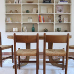 Lot de quatre chaises vintage des années 60 en chêne massif avec assise en paille tressée, style Charlotte Perriand, posées sur un sol en carrelage rouge.