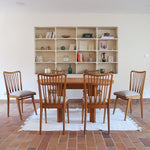 Lot de six chaises vintage scandinaves des années 60 en hêtre massif, dossier à barreaux galbés et assise en tissu clair, posées sur carrelage rouge.