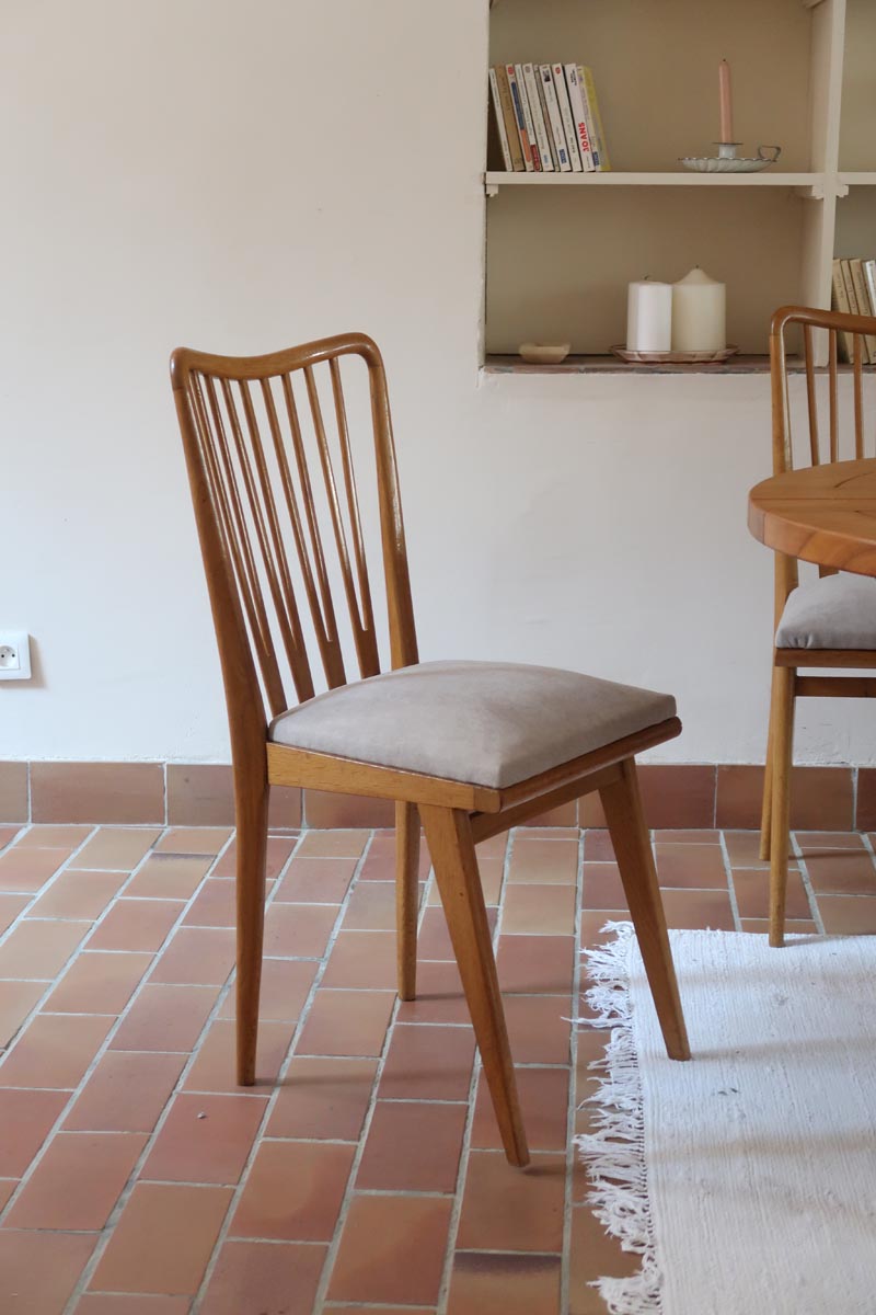 Lot de six chaises vintage scandinaves des années 60 en hêtre massif, dossier à barreaux galbés et assise en tissu clair, posées sur carrelage rouge.