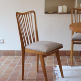 Lot de six chaises vintage scandinaves des années 60 en hêtre massif, dossier à barreaux galbés et assise en tissu clair, posées sur carrelage rouge.