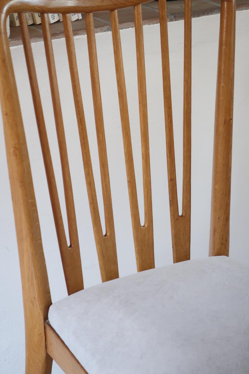 Lot de six chaises vintage scandinaves des années 60 en hêtre massif, dossier à barreaux galbés et assise en tissu clair, posées sur carrelage rouge.