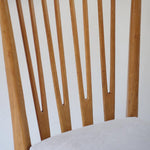 Lot de six chaises vintage scandinaves des années 60 en hêtre massif, dossier à barreaux galbés et assise en tissu clair, posées sur carrelage rouge.