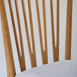 Lot de six chaises vintage scandinaves des années 60 en hêtre massif, dossier à barreaux galbés et assise en tissu clair, posées sur carrelage rouge.