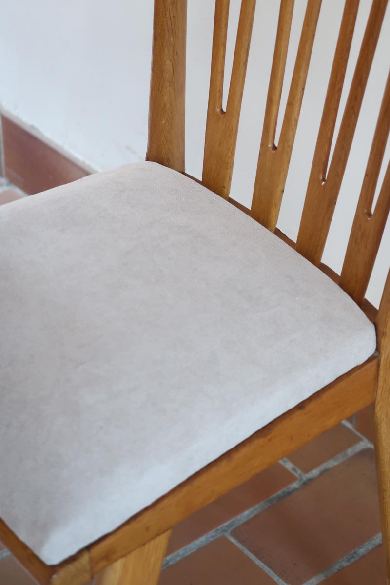 Lot de six chaises vintage scandinaves des années 60 en hêtre massif, dossier à barreaux galbés et assise en tissu clair, posées sur carrelage rouge.