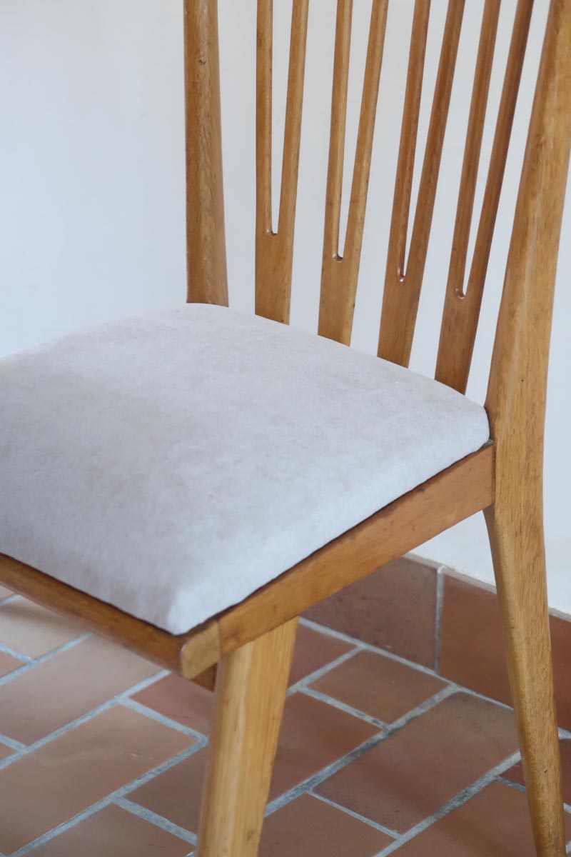 Lot de six chaises vintage scandinaves des années 60 en hêtre massif, dossier à barreaux galbés et assise en tissu clair, posées sur carrelage rouge.