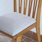 Lot de six chaises vintage scandinaves des années 60 en hêtre massif, dossier à barreaux galbés et assise en tissu clair, posées sur carrelage rouge.