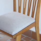 Lot de six chaises vintage scandinaves des années 60 en hêtre massif, dossier à barreaux galbés et assise en tissu clair, posées sur carrelage rouge.