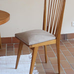 Lot de six chaises vintage scandinaves des années 60 en hêtre massif, dossier à barreaux galbés et assise en tissu clair, posées sur carrelage rouge.