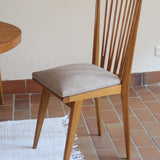 Lot de six chaises vintage scandinaves des années 60 en hêtre massif, dossier à barreaux galbés et assise en tissu clair, posées sur carrelage rouge.