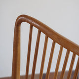 Lot de six chaises vintage scandinaves des années 60 en hêtre massif, dossier à barreaux galbés et assise en tissu clair, posées sur carrelage rouge.