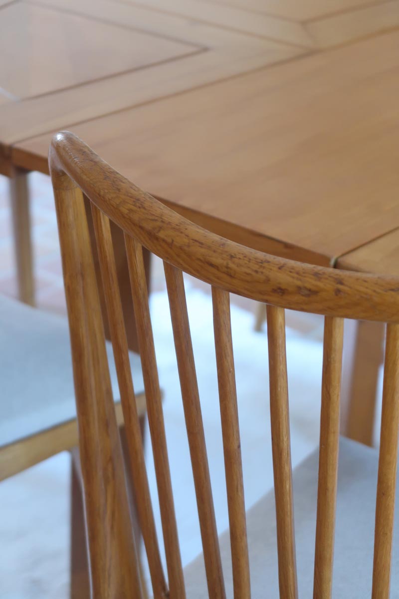 Lot de six chaises vintage scandinaves des années 60 en hêtre massif, dossier à barreaux galbés et assise en tissu clair, posées sur carrelage rouge.