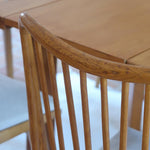 Lot de six chaises vintage scandinaves des années 60 en hêtre massif, dossier à barreaux galbés et assise en tissu clair, posées sur carrelage rouge.