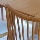 Lot de six chaises vintage scandinaves des années 60 en hêtre massif, dossier à barreaux galbés et assise en tissu clair, posées sur carrelage rouge.