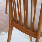 Lot de six chaises vintage scandinaves des années 60 en hêtre massif, dossier à barreaux galbés et assise en tissu clair, posées sur carrelage rouge.