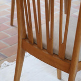 Lot de six chaises vintage scandinaves des années 60 en hêtre massif, dossier à barreaux galbés et assise en tissu clair, posées sur carrelage rouge.