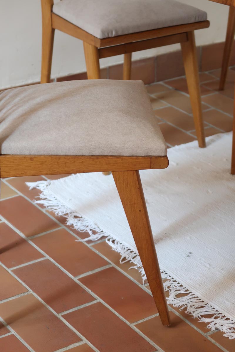 Lot de six chaises vintage scandinaves des années 60 en hêtre massif, dossier à barreaux galbés et assise en tissu clair, posées sur carrelage rouge.