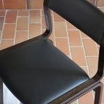 Suite de 6 chaises danoises vintage années 60, bois teinté brun, pieds arrière cintrés filant jusqu'au dossier bandeau, assises et dossiers retapissés en skaï noir