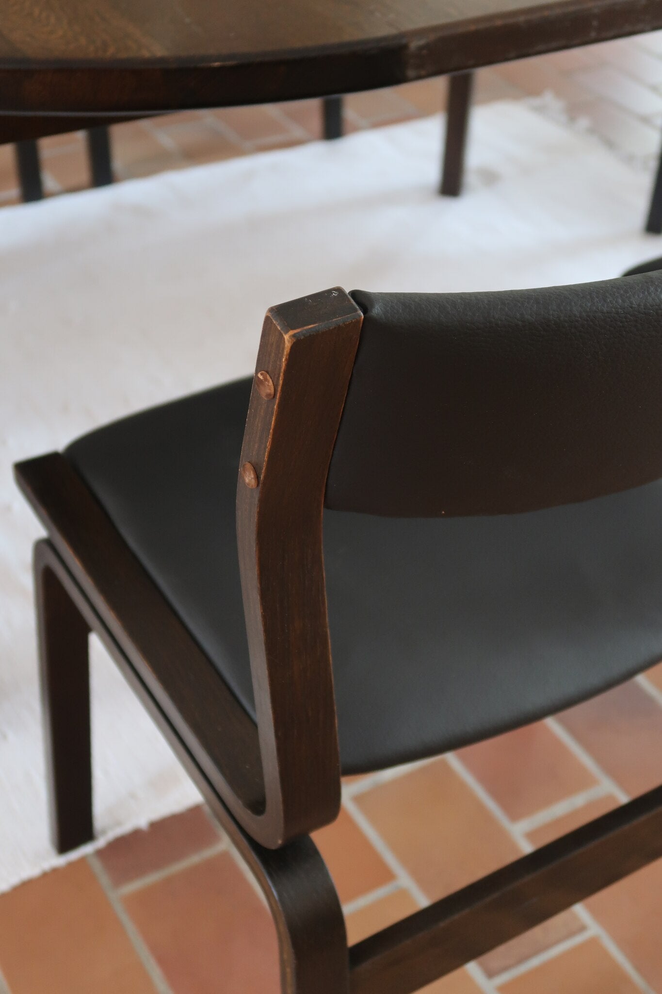 Suite de 6 chaises danoises vintage années 60, bois teinté brun, pieds arrière cintrés filant jusqu'au dossier bandeau, assises et dossiers retapissés en skaï noir