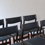 Suite de 6 chaises danoises vintage années 60, bois teinté brun, pieds arrière cintrés filant jusqu'au dossier bandeau, assises et dossiers retapissés en skaï noir