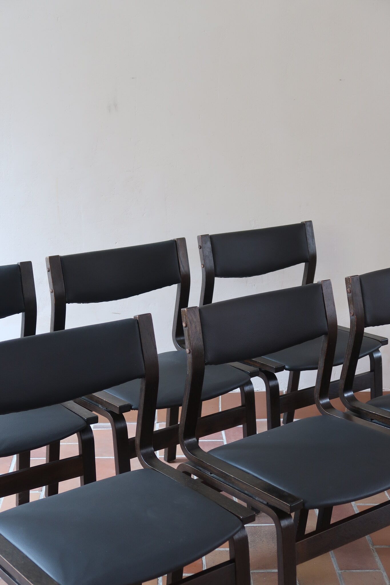 Suite de 6 chaises danoises vintage années 60, bois teinté brun, pieds arrière cintrés filant jusqu'au dossier bandeau, assises et dossiers retapissés en skaï noir