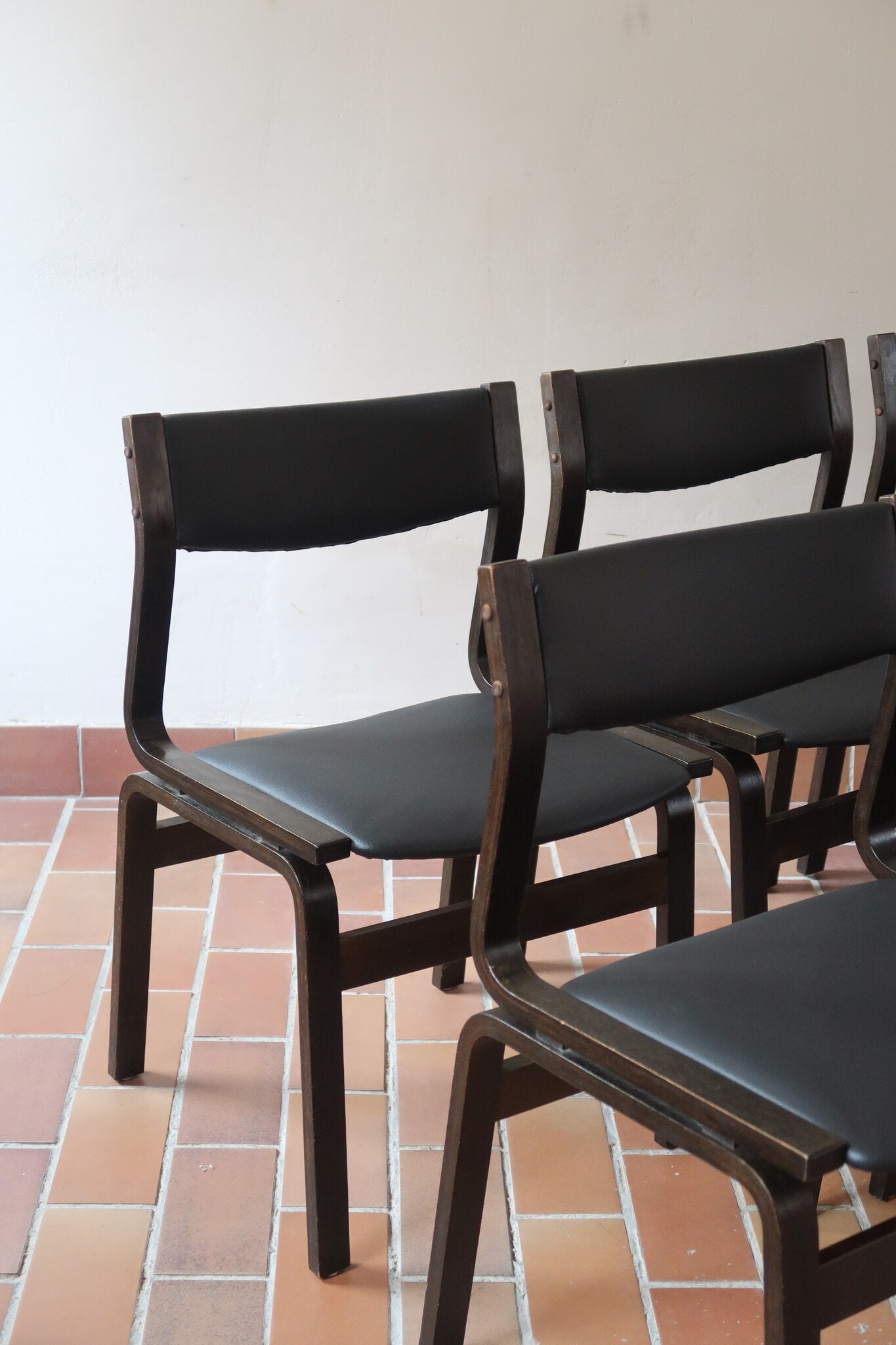 Suite de 6 chaises danoises vintage années 60, bois teinté brun, pieds arrière cintrés filant jusqu'au dossier bandeau, assises et dossiers retapissés en skaï noir