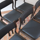 Suite de 6 chaises danoises vintage années 60, bois teinté brun, pieds arrière cintrés filant jusqu'au dossier bandeau, assises et dossiers retapissés en skaï noir