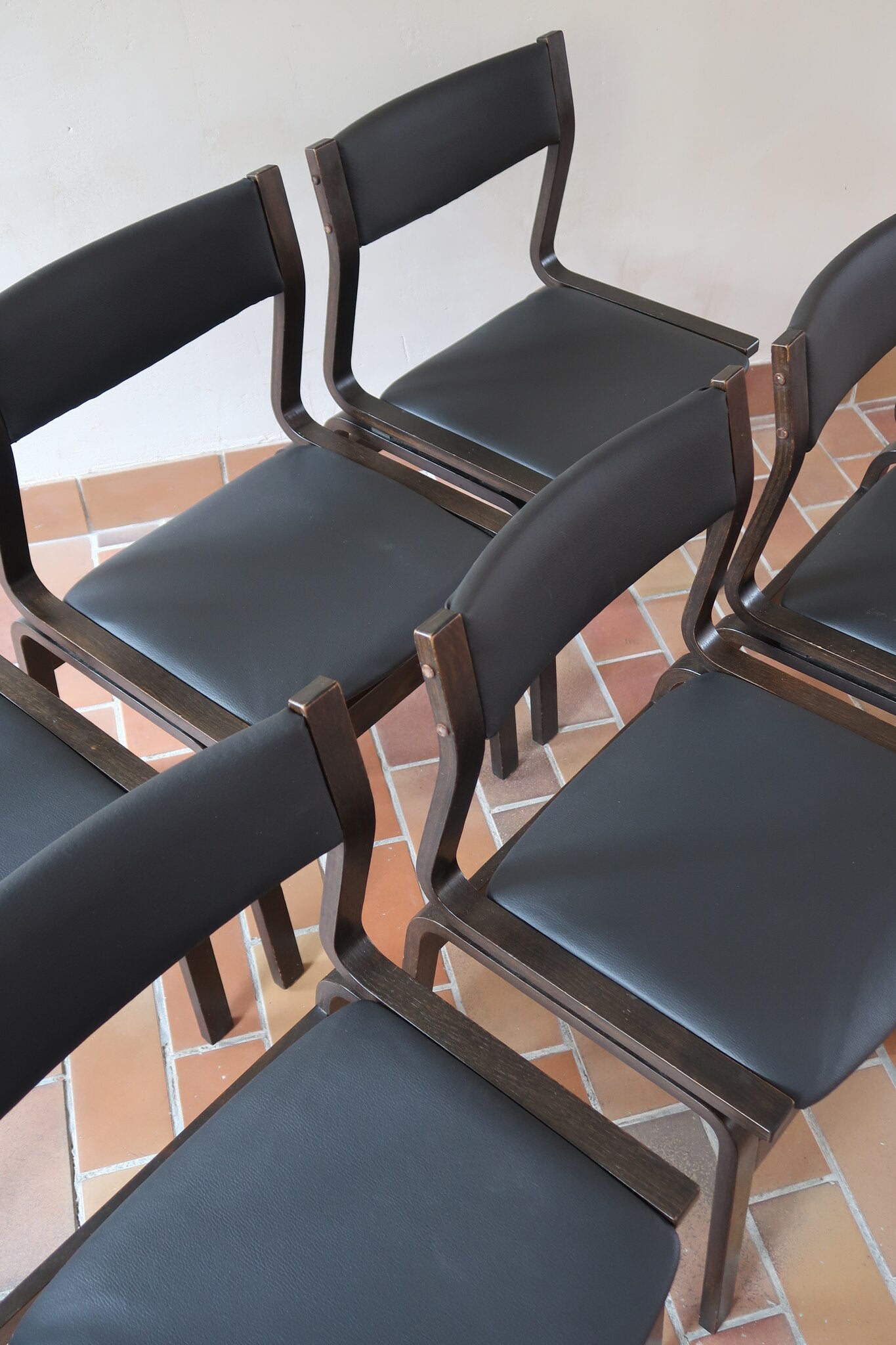 Suite de 6 chaises danoises vintage années 60, bois teinté brun, pieds arrière cintrés filant jusqu'au dossier bandeau, assises et dossiers retapissés en skaï noir