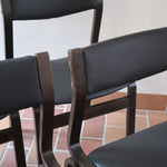 Suite de 6 chaises danoises vintage années 60, bois teinté brun, pieds arrière cintrés filant jusqu'au dossier bandeau, assises et dossiers retapissés en skaï noir