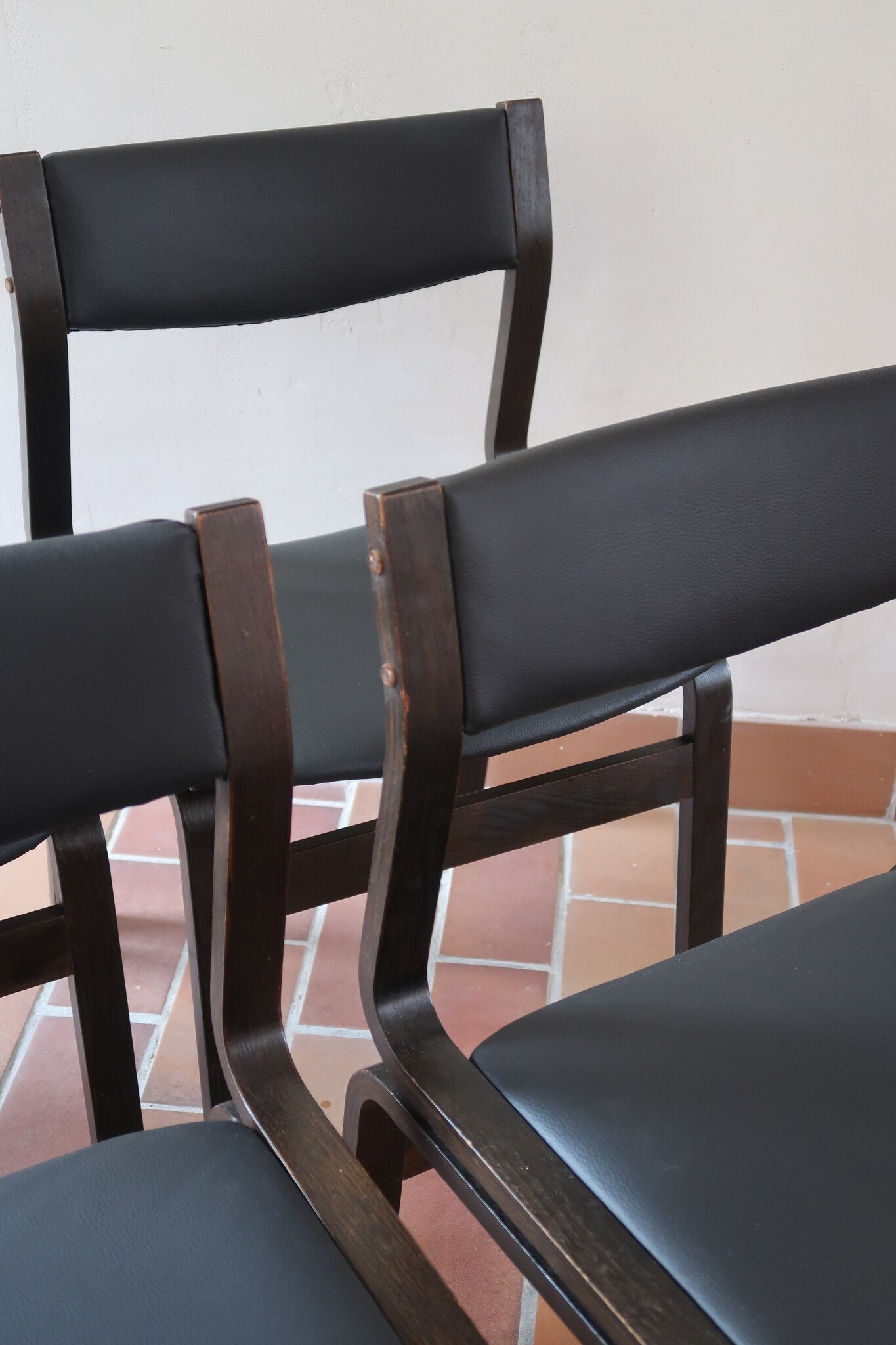 Suite de 6 chaises danoises vintage années 60, bois teinté brun, pieds arrière cintrés filant jusqu'au dossier bandeau, assises et dossiers retapissés en skaï noir