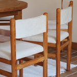 Lot de six chaises vintage des années 80 en pin massif avec assise et dossier en tissu bouclette blanc cassé, style Charlotte Perriand, présentées seules ou mises en situation dans différents espaces.