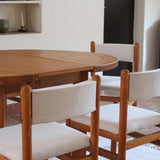 Lot de six chaises vintage des années 80 en pin massif avec assise et dossier en tissu bouclette blanc cassé, style Charlotte Perriand, présentées seules ou mises en situation dans différents espaces.