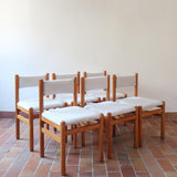 Lot de six chaises vintage des années 80 en pin massif avec assise et dossier en tissu bouclette blanc cassé, style Charlotte Perriand, présentées seules ou mises en situation dans différents espaces.