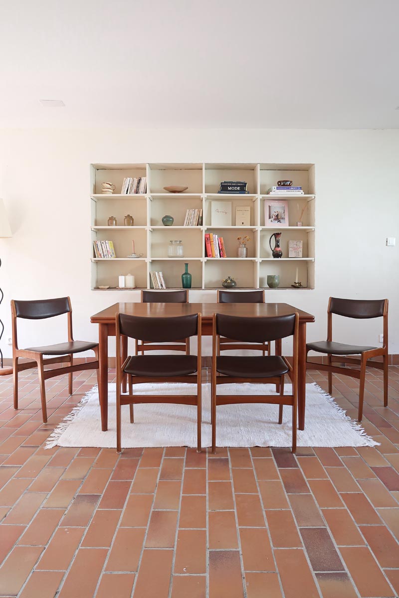 Lot de cinq chaises scandinaves vintage en teck des années 60, style Erik Buch, avec assise et dossier en skaï marron, accompagné d’une sixième chaise offerte présentant une petite déchirure sur le dossier, présentées seules et en mise en situation.