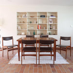 Lot de cinq chaises scandinaves vintage en teck des années 60, style Erik Buch, avec assise et dossier en skaï marron, accompagné d’une sixième chaise offerte présentant une petite déchirure sur le dossier, présentées seules et en mise en situation.