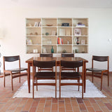 Lot de cinq chaises scandinaves vintage en teck des années 60, style Erik Buch, avec assise et dossier en skaï marron, accompagné d’une sixième chaise offerte présentant une petite déchirure sur le dossier, présentées seules et en mise en situation.