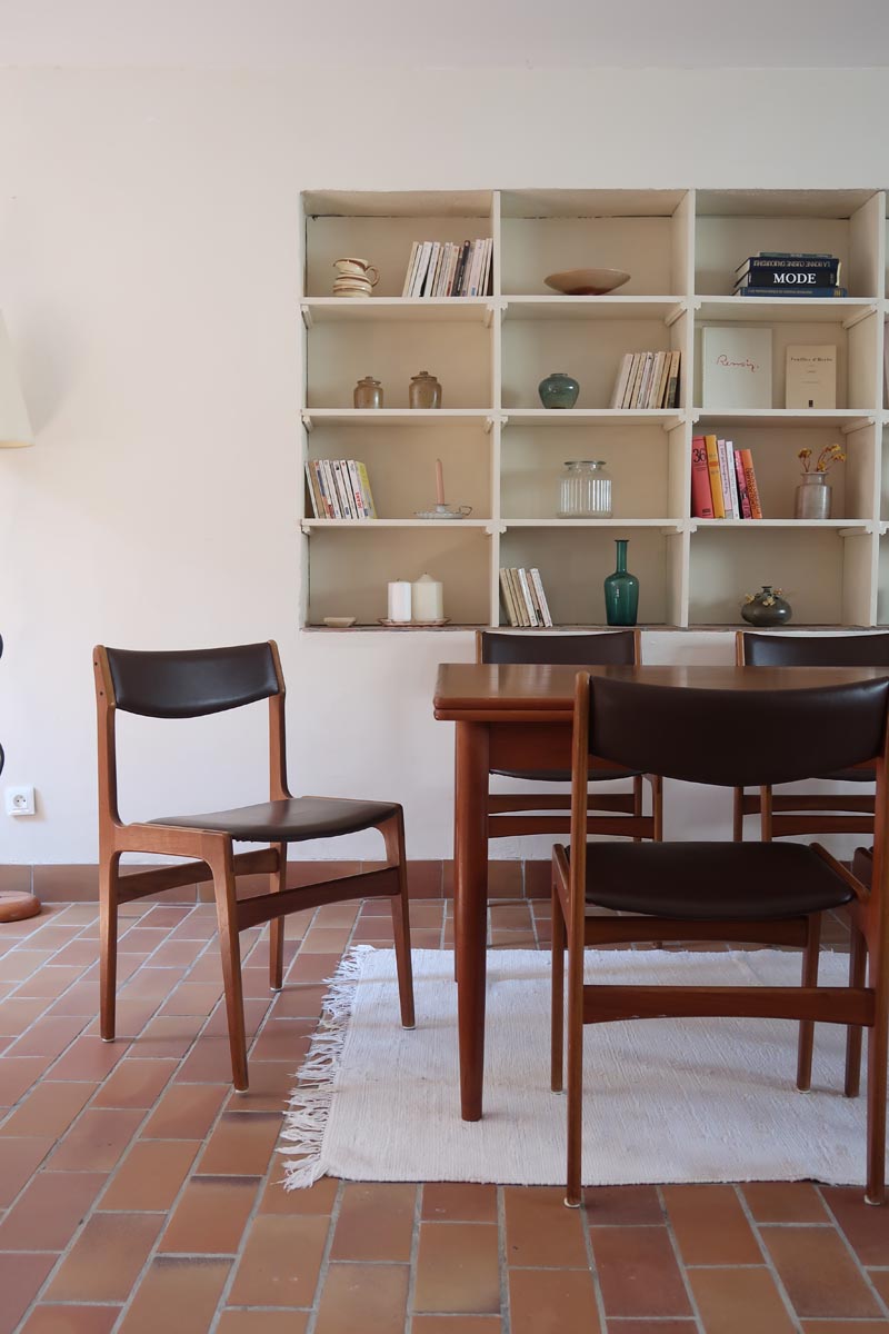 Lot de cinq chaises scandinaves vintage en teck des années 60, style Erik Buch, avec assise et dossier en skaï marron, accompagné d’une sixième chaise offerte présentant une petite déchirure sur le dossier, présentées seules et en mise en situation.