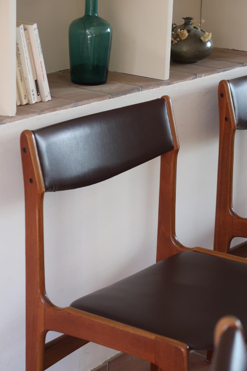 Lot de cinq chaises scandinaves vintage en teck des années 60, style Erik Buch, avec assise et dossier en skaï marron, accompagné d’une sixième chaise offerte présentant une petite déchirure sur le dossier, présentées seules et en mise en situation.