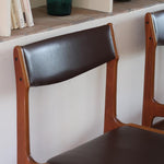 Lot de cinq chaises scandinaves vintage en teck des années 60, style Erik Buch, avec assise et dossier en skaï marron, accompagné d’une sixième chaise offerte présentant une petite déchirure sur le dossier, présentées seules et en mise en situation.