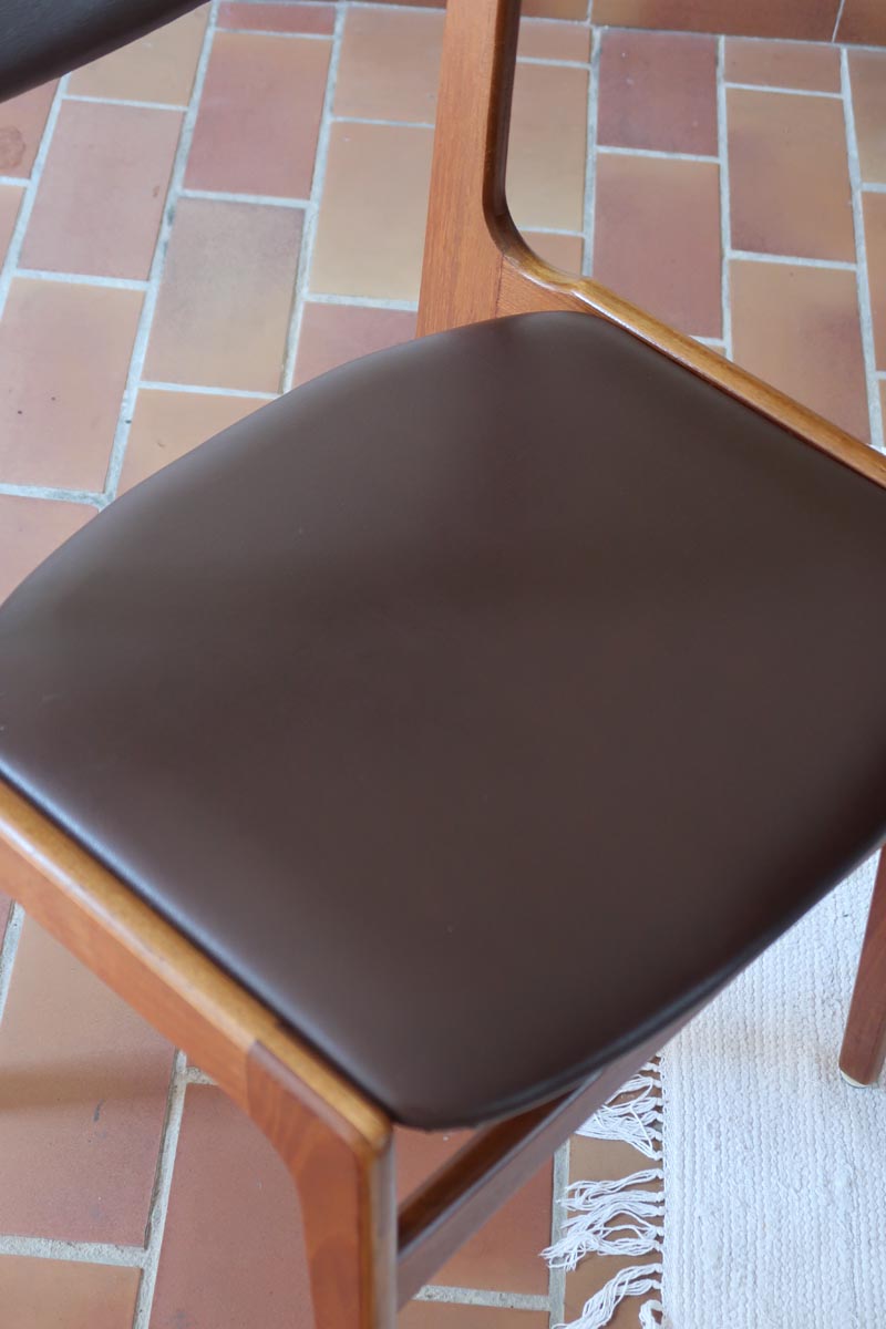 Lot de cinq chaises scandinaves vintage en teck des années 60, style Erik Buch, avec assise et dossier en skaï marron, accompagné d’une sixième chaise offerte présentant une petite déchirure sur le dossier, présentées seules et en mise en situation.