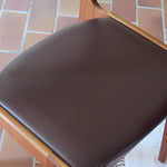 Lot de cinq chaises scandinaves vintage en teck des années 60, style Erik Buch, avec assise et dossier en skaï marron, accompagné d’une sixième chaise offerte présentant une petite déchirure sur le dossier, présentées seules et en mise en situation.