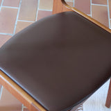 Lot de cinq chaises scandinaves vintage en teck des années 60, style Erik Buch, avec assise et dossier en skaï marron, accompagné d’une sixième chaise offerte présentant une petite déchirure sur le dossier, présentées seules et en mise en situation.