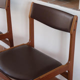 Lot de cinq chaises scandinaves vintage en teck des années 60, style Erik Buch, avec assise et dossier en skaï marron, accompagné d’une sixième chaise offerte présentant une petite déchirure sur le dossier, présentées seules et en mise en situation.
