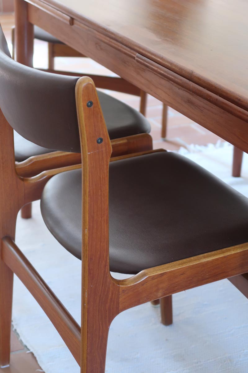 Lot de cinq chaises scandinaves vintage en teck des années 60, style Erik Buch, avec assise et dossier en skaï marron, accompagné d’une sixième chaise offerte présentant une petite déchirure sur le dossier, présentées seules et en mise en situation.