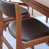 Lot de cinq chaises scandinaves vintage en teck des années 60, style Erik Buch, avec assise et dossier en skaï marron, accompagné d’une sixième chaise offerte présentant une petite déchirure sur le dossier, présentées seules et en mise en situation.