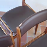 Lot de cinq chaises scandinaves vintage en teck des années 60, style Erik Buch, avec assise et dossier en skaï marron, accompagné d’une sixième chaise offerte présentant une petite déchirure sur le dossier, présentées seules et en mise en situation.